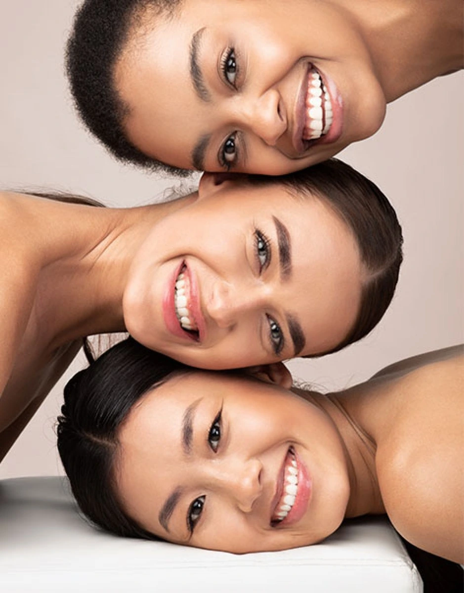Portrait von drei lächelnden Frauen, die ihre Köpfe aufeinander legen